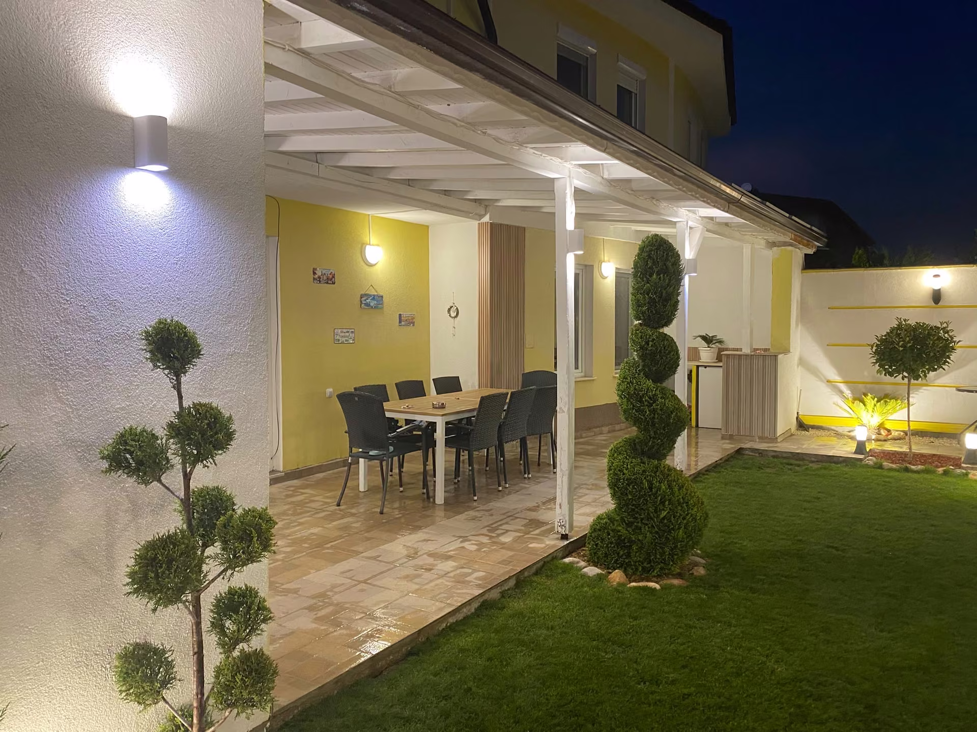 Pérgola y comedor exterior iluminados de noche