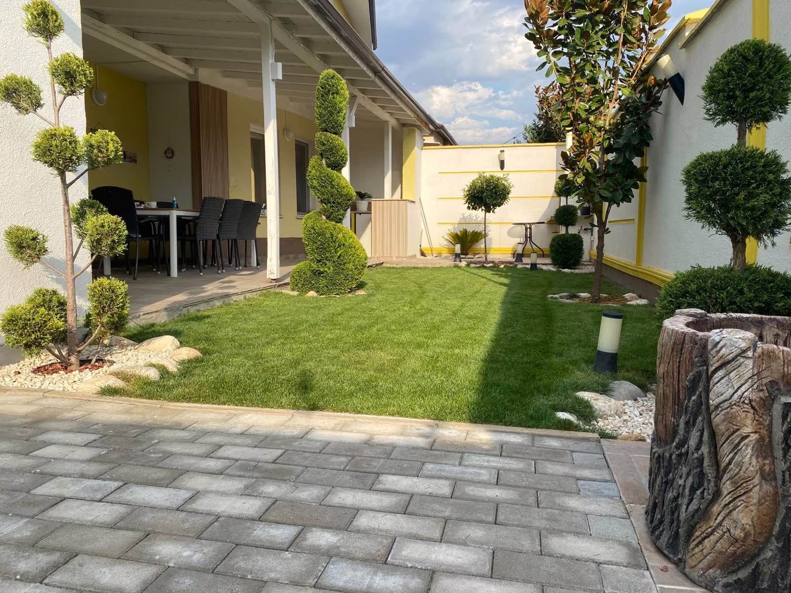 Patio, césped y topiarios en un jardín residencial